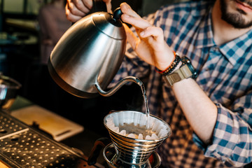 Alternative Coffee Brewing Method. Close-up of barista hand pouring water from the kettle to coffee filter purover in the restaurant.