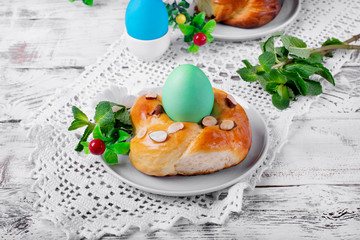 Easter yeast bun ring with almond and colored egg in the middle on the white wooden table