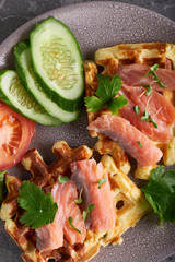 Homemade waffles with salmon, cucumber and herbs on plate