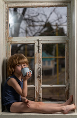 Obraz premium a boy with blond hair sits on a windowsill