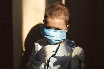 Seriously little boy in medical uniform playing with stethoscope