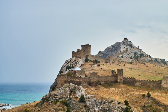 View of walls of ancient sudak fortress in Crimea against blue sky and sea.