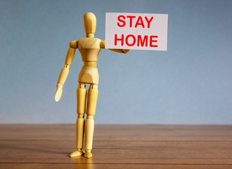 COVID-19 Pandemic Coronavirus concept. Wooden model of a man holding a white card saying stay home.