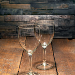 Pair of empty wine glasses against a rustic wood background.