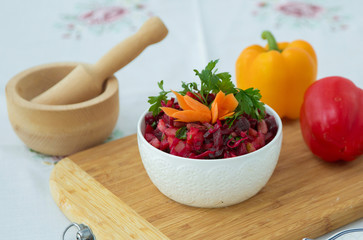Slices of boiled beets in a plate. Healthy food, diet salad with beets . Fresh colorful salad: beets, carrots, cabbage served on a wooden board, decorated with capers .