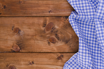 Blue checkered kitchen tablecloth on rustic wooden table. Free space for text. Oktoberfest traditional ornament.