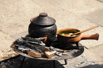 cooking delicious lunch while camping, an iron pot full of soup brewed over an open fire
