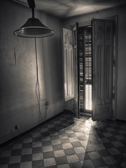 Habitación de casa abandonada con puertas de balcón abiertas y persiana que ilumina en la...