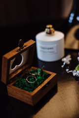 Two gold wedding rings in a beautiful wooden casket with green moss. Wedding accessories. Bride morning. Film noise