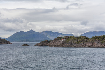 Norwegian fjord and mountains surrounded by clouds, ideal fjord reflection in clear water. selective focus.
