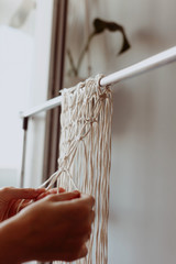 The girl weaves macrame. Boho decor in the process of weaving. Hand made