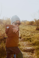 A boy rides a balance bike in a clearing. Spring mood. Sun