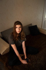 portrait of a girl with brown hair, sitting at home on the bed, looking at the camera