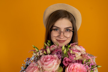 Joyful girl in hat holding eustoma flowers isolated on yellow background