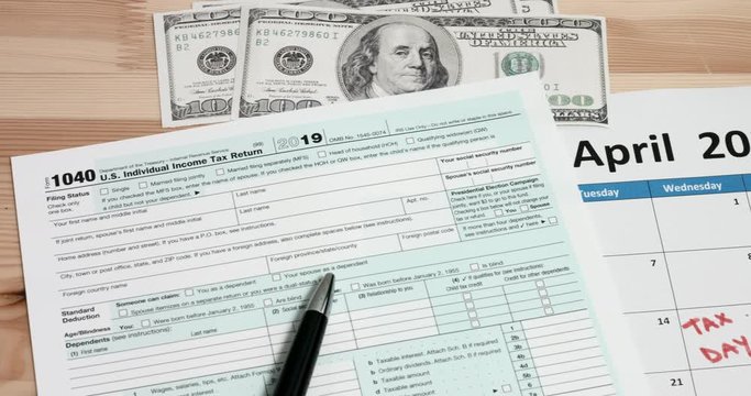 US 1040 tax day return form with 100 usd dollar bills and calendar