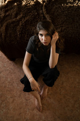 Fototapeta na wymiar Portrait of a girl with brown hair sitting at home on the floor by the sofa, looking at the camera