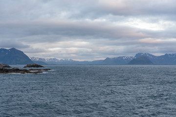 Norwegian fjord and mountains surrounded by clouds, midnight sun, polar day, ideal fjord reflection in clear water. selective focus.