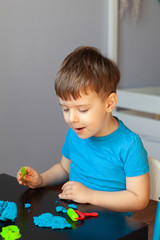 Boy playing with colorful clay molding in your room a Small child sculpts at home. Educational games for preschool children
