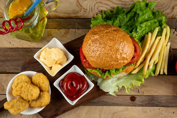 Hamburger,chicken nuggets and fried potato sticks with sauces, top view