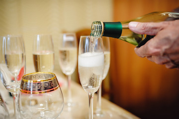 Сhampagne poured in a crystal glass. The male hand holds a big bottle