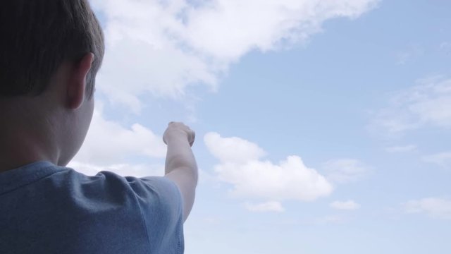 Boy pointing hand to blue sky and draw with finger clouds