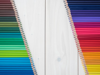 two rows of colored pencils on wooden background