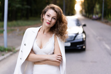 Beautiful woman in elegant outfit standing near car