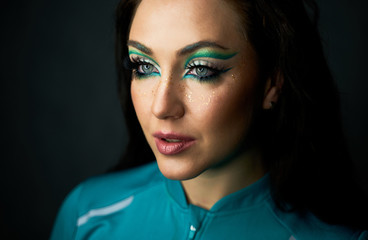 Beautiful young girl in the studio . The face of a young beautiful girl with a bright green make-up.  Fashion, beauty, make-up, cosmetics, hairstyle, beauty salon, boutique, discounts, sales.