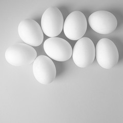 Beautiful smooth eggs on a light monochrome background. High key, black and white image.