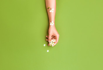 Woman's hand in spring flowers on a green background. The concept of organic bio cosmetics, skin...