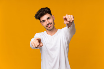 Fototapeta premium Young man over isolated orange background points finger at you while smiling