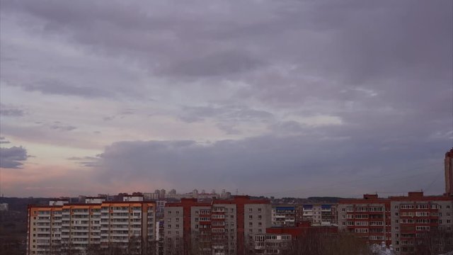 Timelapse footage: panorama over the city, at sunset clouds go beyond the horizon
