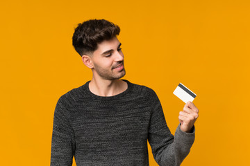 Young man over isolated background holding a credit card