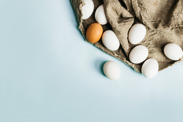 Fresh natural eggs lie on a fabric, on a blue background. Bright Easter holiday, symbol, cooking,close up