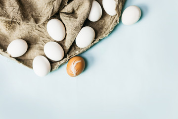 Fresh natural eggs lie on a fabric, on a blue background. Bright Easter holiday, symbol, cooking,close up