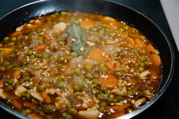Close-up photograph of a pan cooking a rice and chicken paella in Spain during confinement