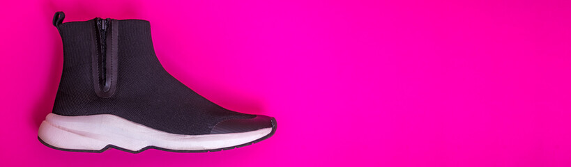 Beautiful fashionable socks sneakers on a pink background. Minimal design of . Stylish black sneakers. Training time concept.