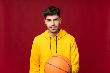 Young man over isolated background with ball of basketball