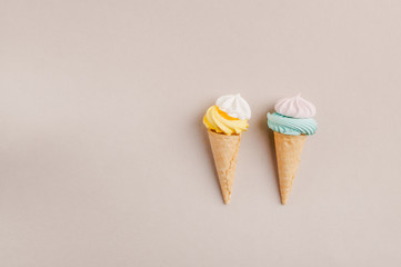 Small crispy waffle ice cream cups with colored marshmallows on a pastel background