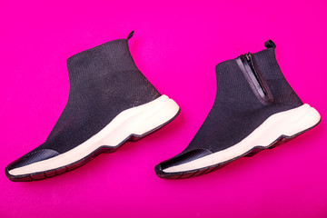 Beautiful fashionable socks sneakers on a pink background. Minimal design of . Stylish black sneakers. Training time concept.