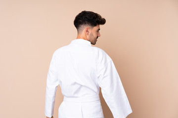 Young man over isolated background doing karate in back position