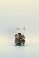 Metal coins, Russian rubles, lie in a transparent glass jar on a light background. Place for text and design.