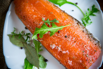 piece of salty red fish with different seasonings and herbs in a plate