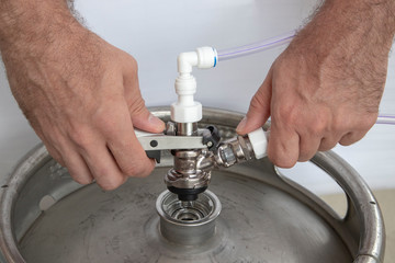 The hands hold the pusher swivel head on the beer above the keg