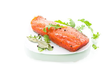 piece of salty red fish with different seasonings and herbs in a plate