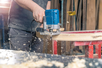 milling round wooden window by hand electric cutter in joinery