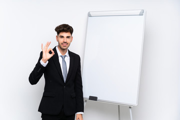 Young businessman giving a presentation on white board showing ok sign with fingers