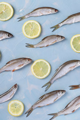 Pattern of small fish with lemon slices on a blue background, Top view, Vertical format