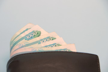 Leather brown wallet with Russian money sticking out of it in banknotes