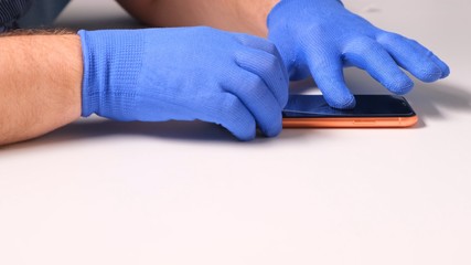 male hands in blue gloves replaces a broken tempered glass screen protector for a smartphone. A man prepares a smartphone to replace glass. Smartphone repair concept. copy space